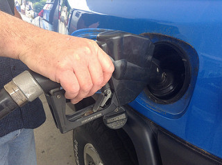 A hand and gas pump filling a gas tank